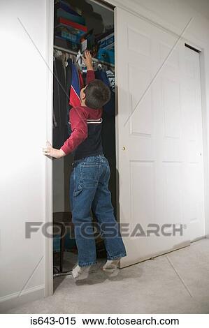 Boy trying to reach shelf in wardrobe View Large Photo Image Stock Photography - Boy trying to reach shelf in wardrobe. Fotosearch