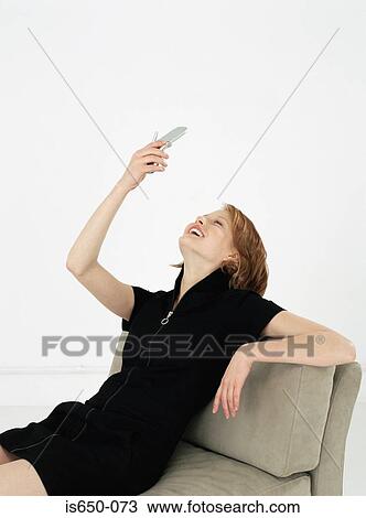 Stock Image - Young woman looking up at her mobile phone. Fotosearch