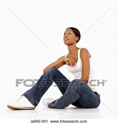 Stock Image - Young woman sitting down looking thoughtful. Fotosearch