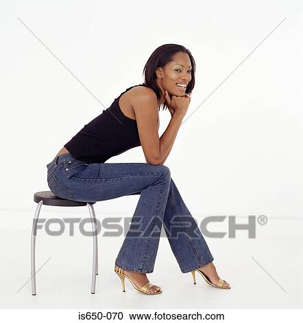 Young woman sitting on stool View Large Photo Image Stock Image - Young woman sitting on stool. Fotosearch