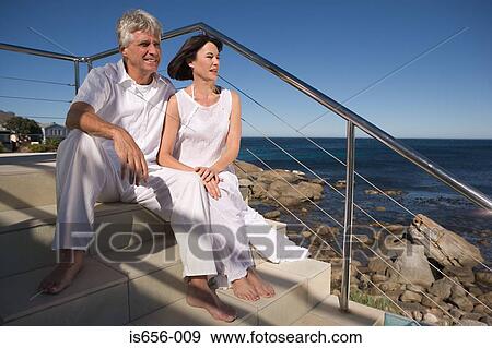 Mature couple sitting by the sea View Large Photo Image Stock Photo - Mature couple sitting by the sea. Fotosearch