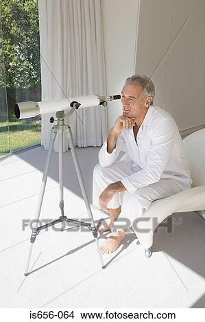 Mature man looking through telescope View Large Photo Image Picture - Mature man looking through telescope. Fotosearch
