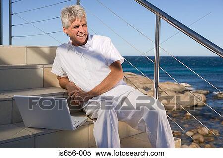 Mature man with laptop by the sea View Large Photo Image Stock Photography - Mature man with laptop by the sea. Fotosearch