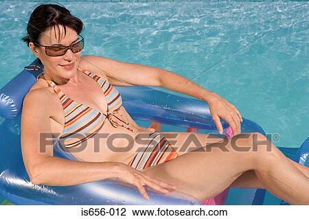 Stock Image - Woman on inflatable in swimming pool . Fotosearch