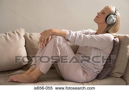 Stock Photography - Woman on sofa wearing haedphones . Fotosearch