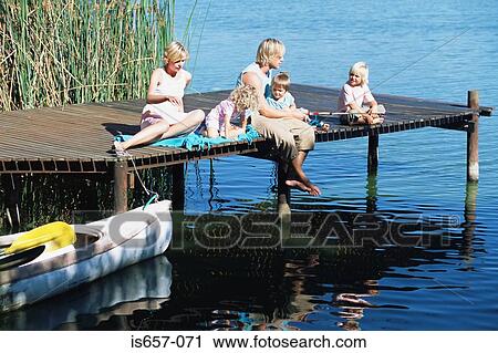 Stock Image - Family sitting on a jetty . Fotosearch