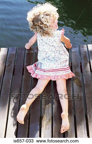 Stock Image - Girl lying on a jetty. Fotosearch
