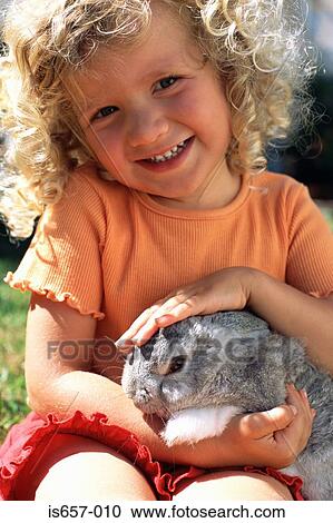 Girl stroking a rabbit View Large Photo Image Stock Image - Girl stroking a rabbit. Fotosearch