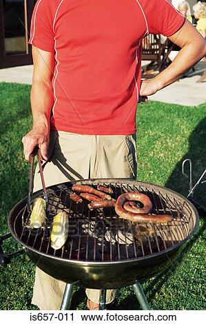 Man cooking food on a barbecue View Large Photo Image Stock Image - Man cooking food on a barbecue. Fotosearch