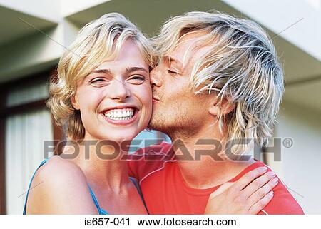 Stock Image - Man kissing wife on the cheek. Fotosearch