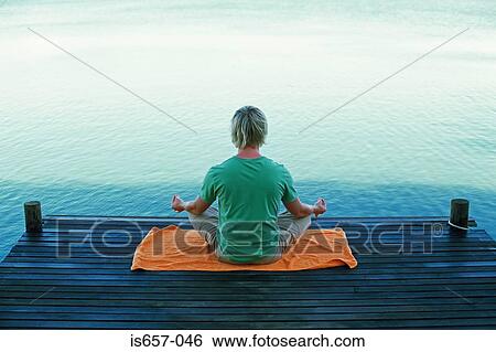 Stock Photograph - Man meditating by water. Fotosearch