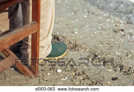 Stock Image - Person in rubber boots sitting in deck chair . Fotosearch
