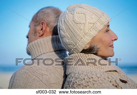 Stock Image - Senior couple back to back on beach. Fotosearch