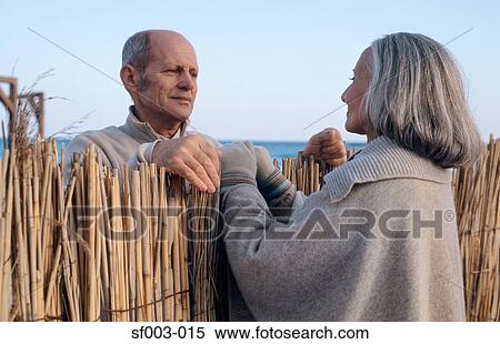 Stock Photography - Senior couple looking at each other over fence. Fotosearch