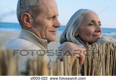 Senior couple on beach looking over fence View Large Photo Image Stock Image - Senior couple on beach looking over fence. Fotosearch