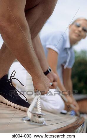 Couple on boat securing a rope View Large Photo Image Stock Image - Couple on boat securing a rope. Fotosearch