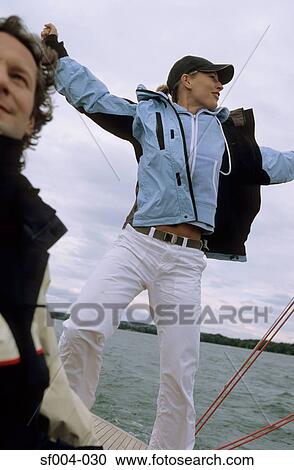 Stock Image - Couple on boat woman stretching her arms out. Fotosearch