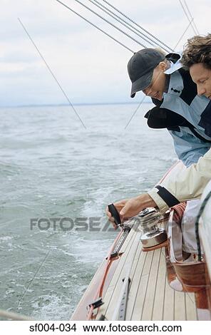 Couple turning crank handle on boat View Large Photo Image Picture - Couple turning crank handle on boat. Fotosearch