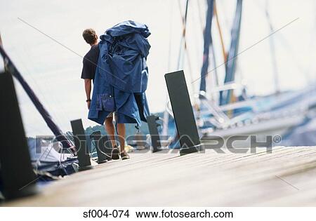 Man walking along jetty carrying boat cover View Large Photo Image Picture - Man walking along jetty carrying boat cover. Fotosearch