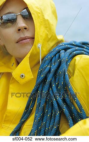 Woman in yellow raincoat and sunglasses with rope over her shoulder View Large Photo Image Stock Image - Woman in yellow raincoat and sunglasses with rope over her shoulder. Fotosearch