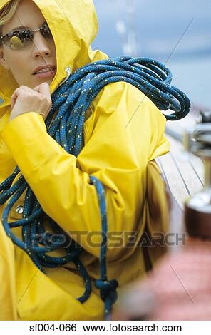 Woman in yellow raincoat and sunglasses carrying rope View Large Photo Image Stock Photograph - Woman in yellow raincoat and sunglasses carrying rope. Fotosearch