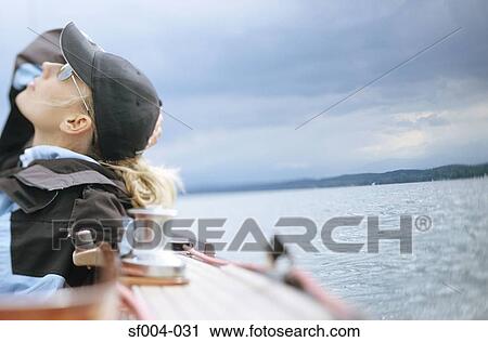 Woman on boat looking up at cloudy sky View Large Photo Image Stock Image - Woman on boat looking up at cloudy sky. Fotosearch