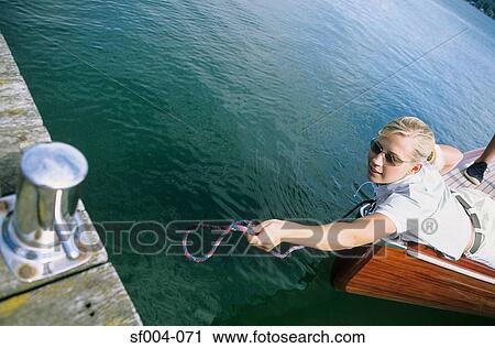 Stock Image - Woman on boat reaching for jetty. Fotosearch