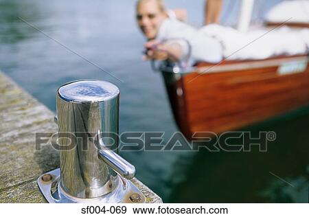 Woman on boat reaching out towards bollard on jetty View Large Photo Image Stock Photo - Woman on boat reaching out towards bollard on jetty. Fotosearch