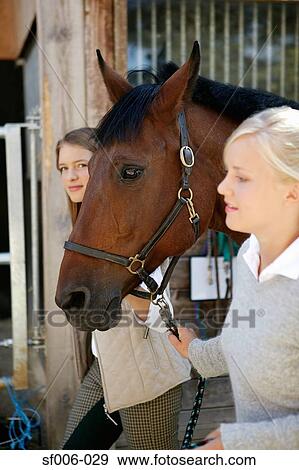 Stock Photo - Two young women leading a horse. Fotosearch