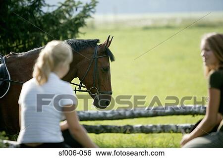 Stock Photograph - Two young women with a horse. Fotosearch