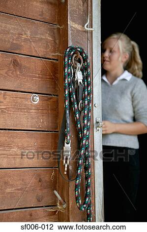 Stock Image - Young woman at stable door. Fotosearch