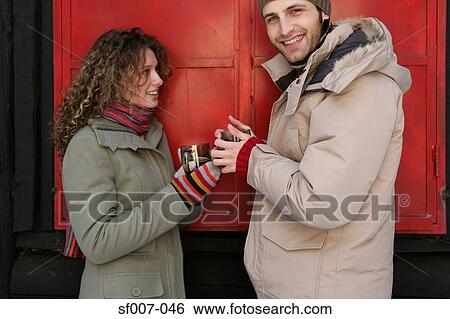 Couple in winter clothes with warm drinks View Large Photo Image Stock Photograph - Couple in winter clothes with warm drinks. Fotosearch
