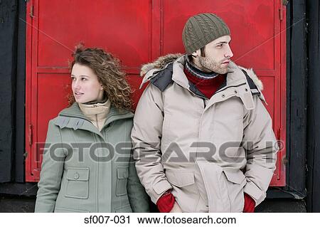 Stock Image - Couple standing outside a hut. Fotosearch