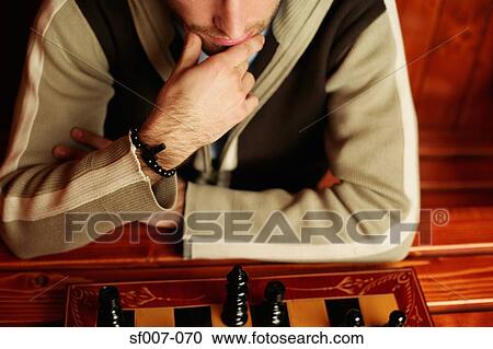 Stock Image - Man contemplating chess move. Fotosearch