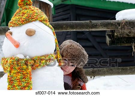 Picture - Woman hiding behind snowman. Fotosearch
