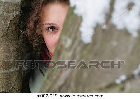 Young woman hiding behind tree View Large Photo Image Stock Photo - Young woman hiding behind tree. Fotosearch