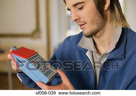 Stock Photo - Man holding a model house. Fotosearch