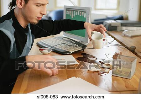 Stock Image - Man with coffee spilt on his desk. Fotosearch