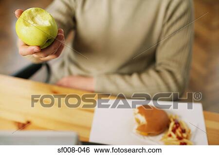 Man with half eaten apple and cheeseburger View Large Photo Image Stock Photograph - Man with half eaten apple and cheeseburger. Fotosearch