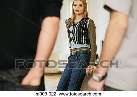 Stock Image - Two young men approaching a young woman. Fotosearch