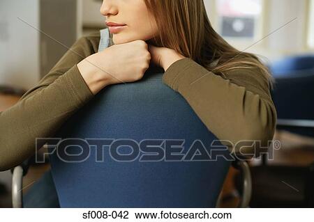 Young woman resting on back of chair View Large Photo Image Stock Image - Young woman resting on back of chair. Fotosearch