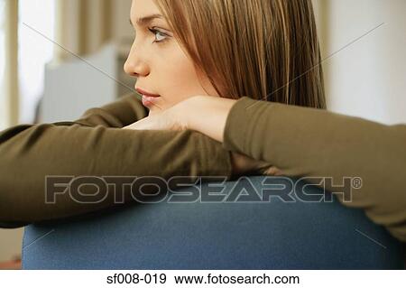 Young woman resting on back of chair View Large Photo Image Stock Photo - Young woman resting on back of chair. Fotosearch