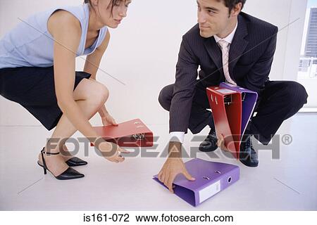 Stock Image - Businessman picking up folders for colleague. Fotosearch