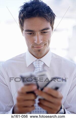Stock Photograph - Man choosing between mobile phones. Fotosearch