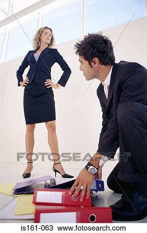 Man picking up folders for angry woman View Large Photo Image Stock Image - Man picking up folders for angry woman. Fotosearch