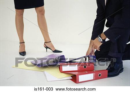 Stock Image - Man picking up folders for woman. Fotosearch
