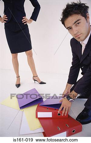 Stock Photo - Man picking up folders for woman. Fotosearch