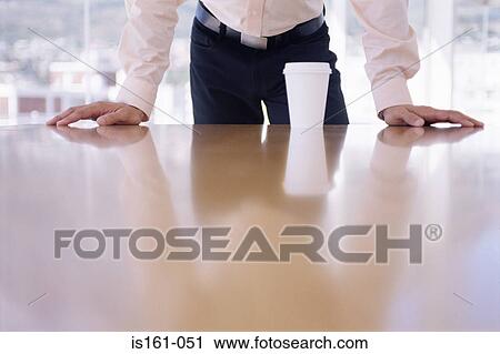 Stock Image - Office worker leaning on desk. Fotosearch