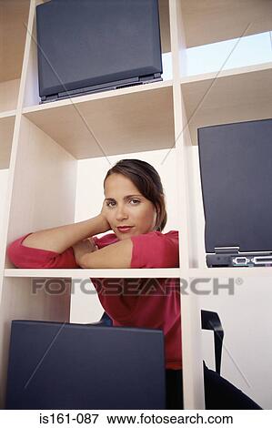Stock Photo - Woman leaning on bookcase. Fotosearch
