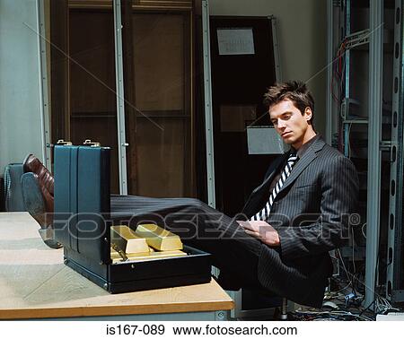 Stock Photo - Businessman looking at briefcase of gold bars. Fotosearch